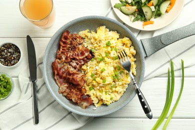 Photo of Tasty brunch. Delicious scrambled eggs, bacon, salad and glass of juice served on white wooden table, flat lay