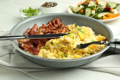 Photo of Tasty brunch. Delicious scrambled eggs, bacon and salad served on white wooden table, closeup