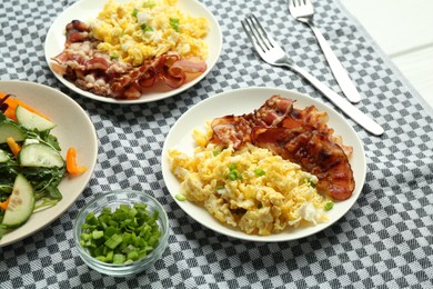 Photo of Tasty brunch. Delicious scrambled eggs, bacon and salad served on white table