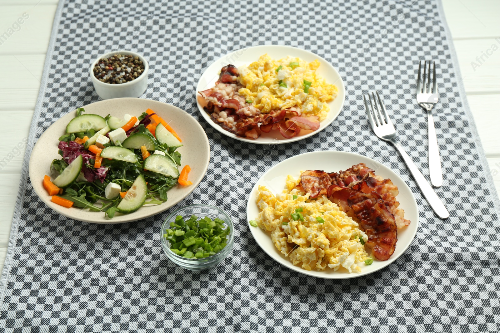 Photo of Tasty brunch. Delicious scrambled eggs, bacon and salad served on white wooden table