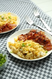 Photo of Tasty brunch. Delicious scrambled eggs and bacon served on white table, closeup