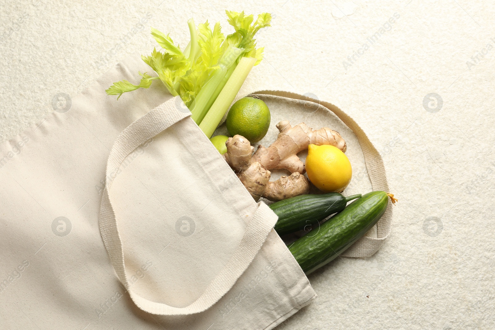 Photo of Eco bag with vegetables, fruits and ginger on white textured table, top view