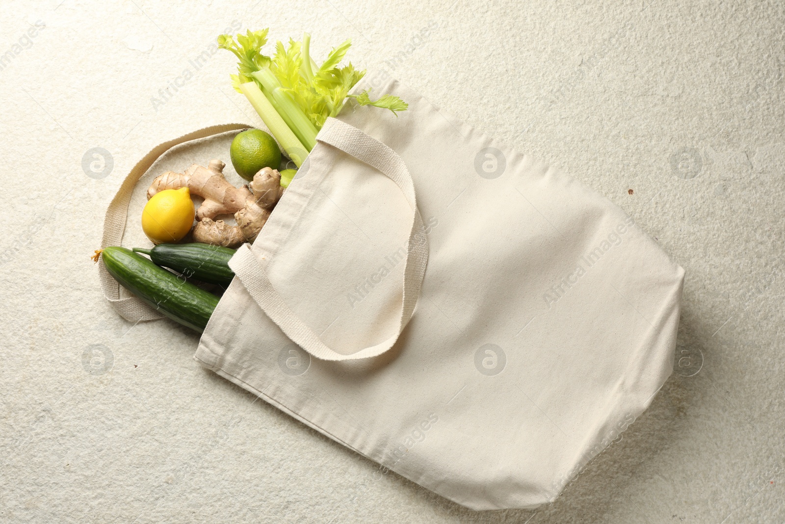 Photo of Eco bag with vegetables, fruits and ginger on white textured table, top view