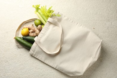 Photo of Eco bag with vegetables, fruits and ginger on white textured table, top view