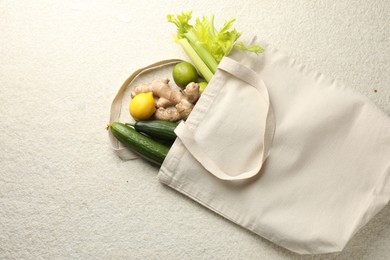 Photo of Eco bag with vegetables, fruits and ginger on white textured table, top view. Space for text