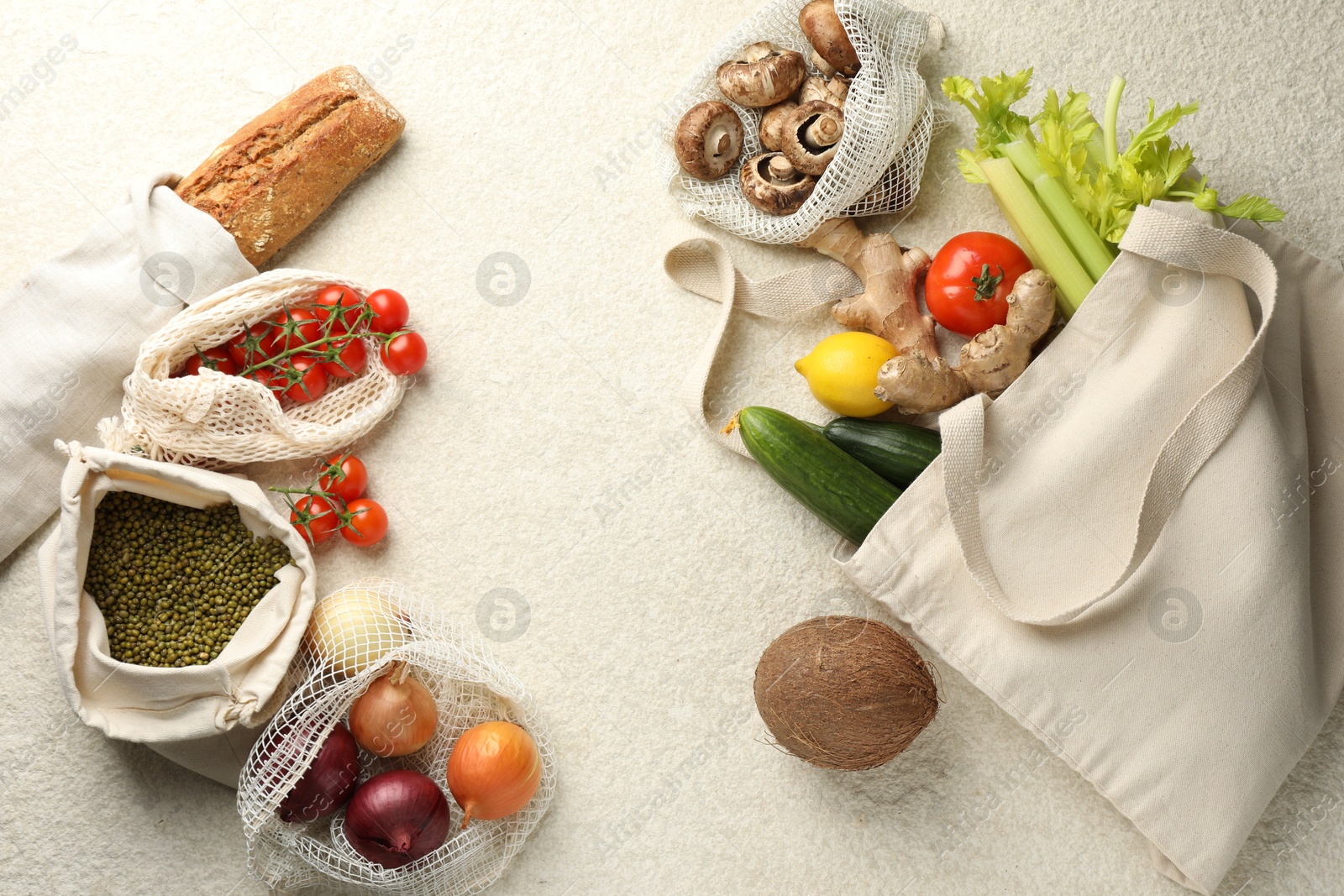 Photo of Eco bags with different food products on white textured table, flat lay. Space for text