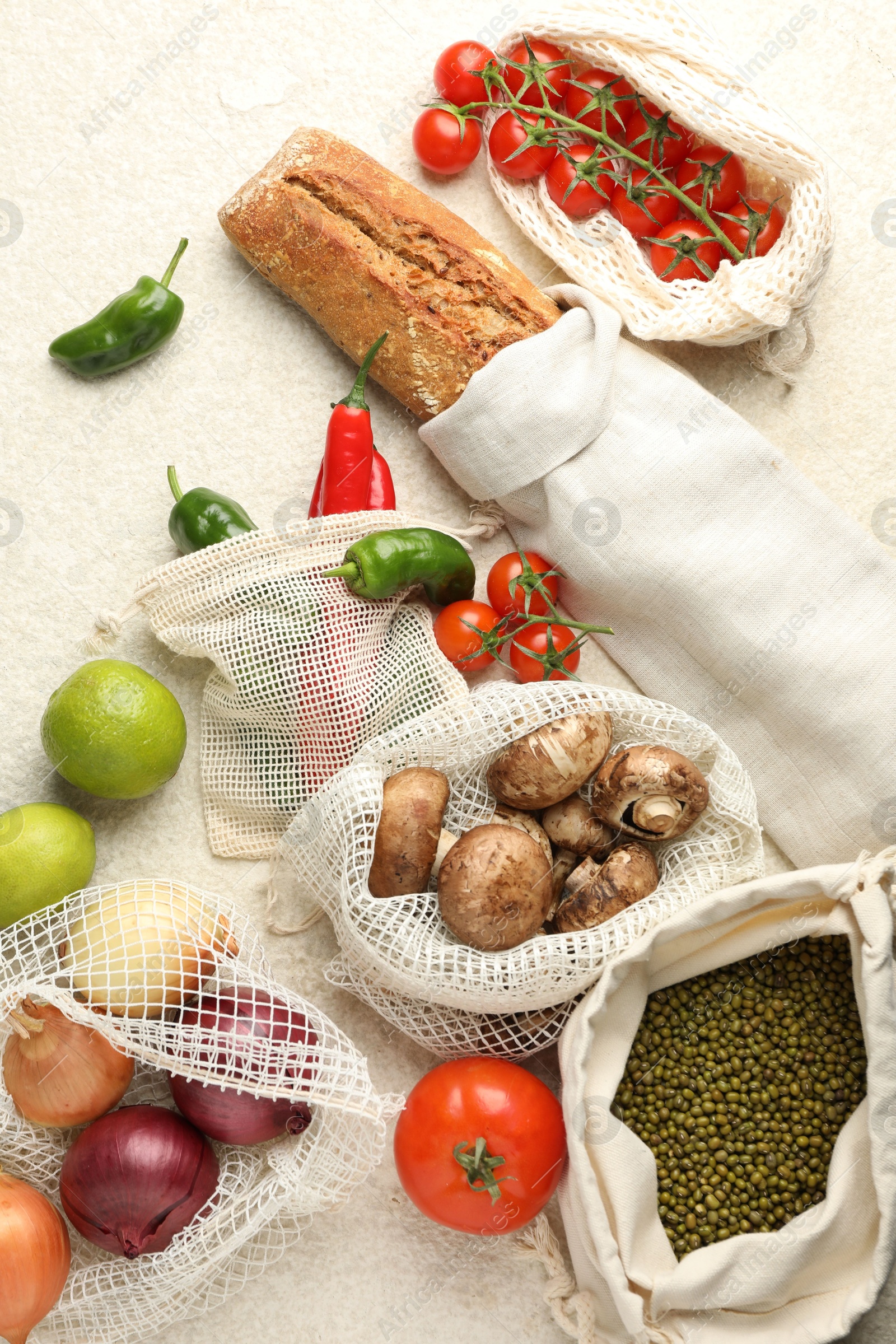 Photo of Eco bags with different food products on white textured table, flat lay