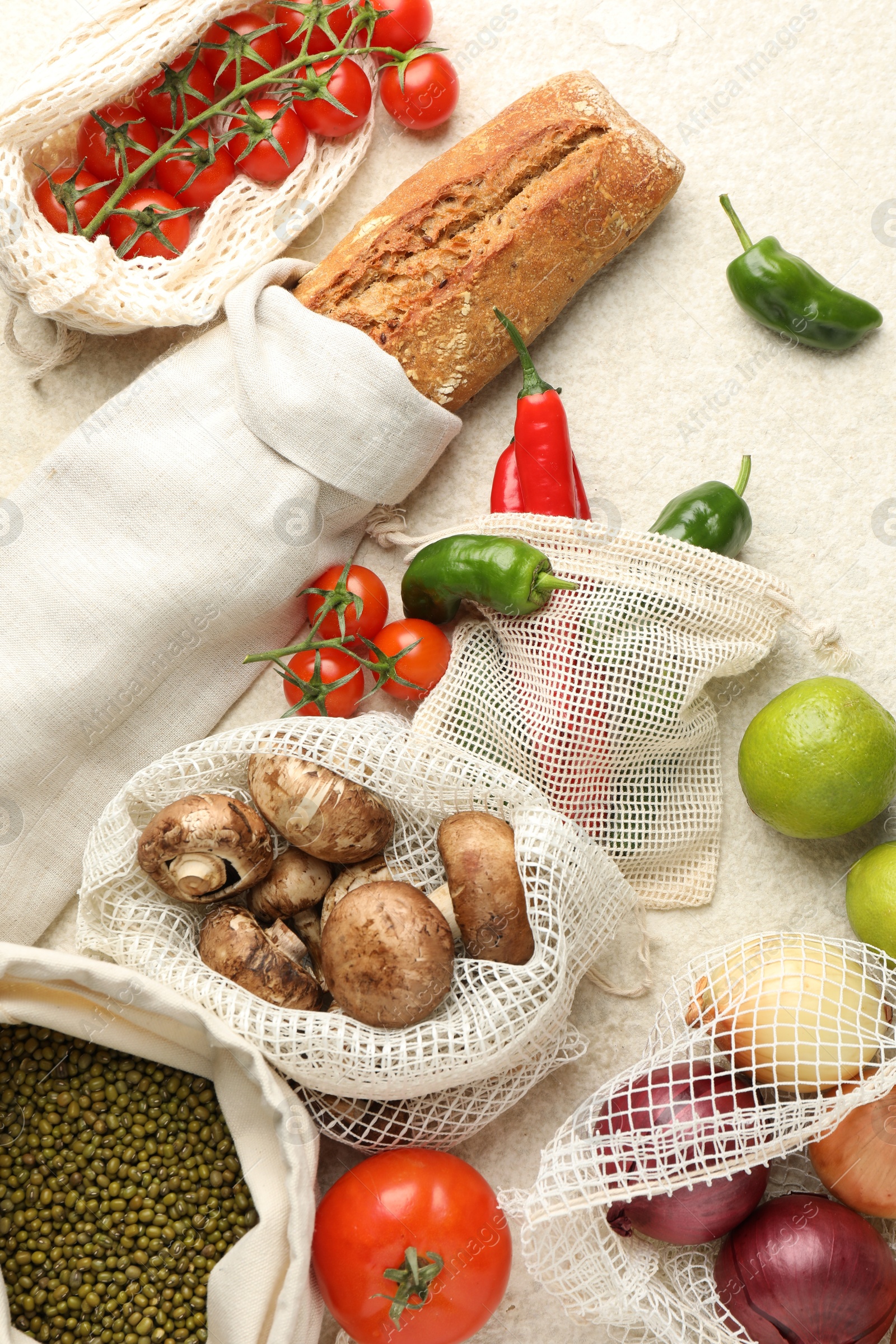 Photo of Eco bags with different food products on white textured table, flat lay