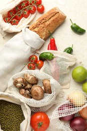 Photo of Eco bags with different food products on white textured table, flat lay