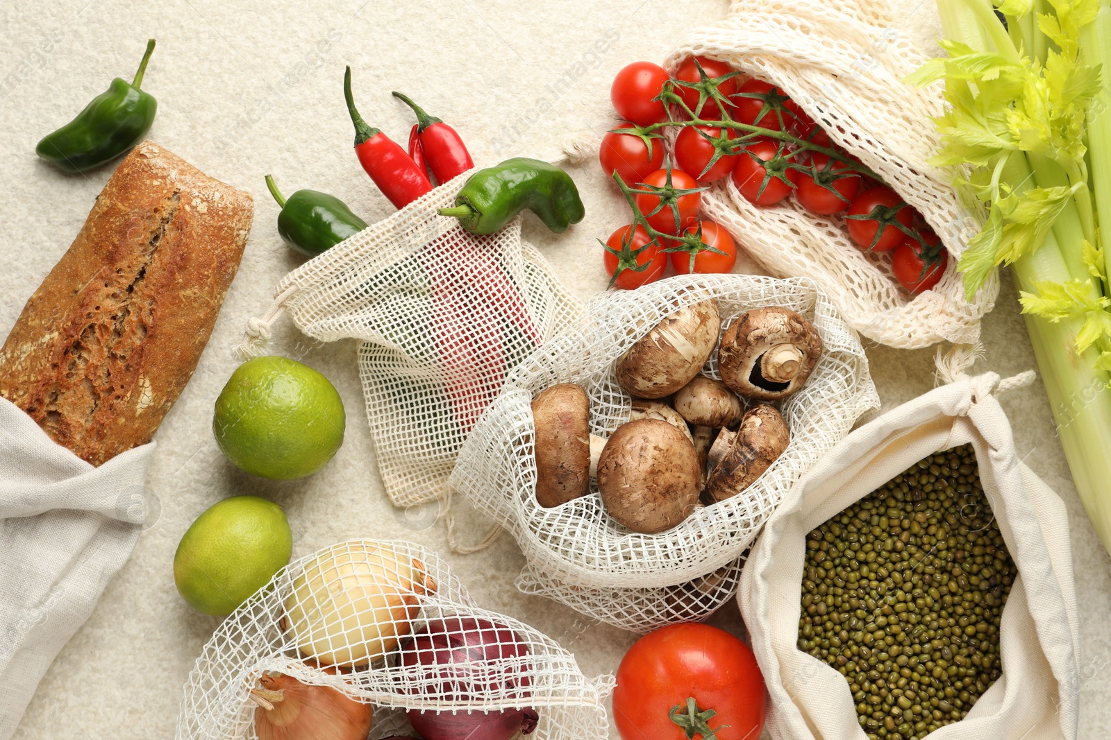 Photo of Eco bags with different food products on white textured table, flat lay