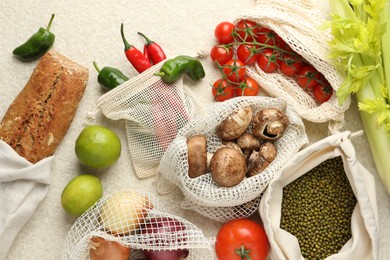 Photo of Eco bags with different food products on white textured table, flat lay