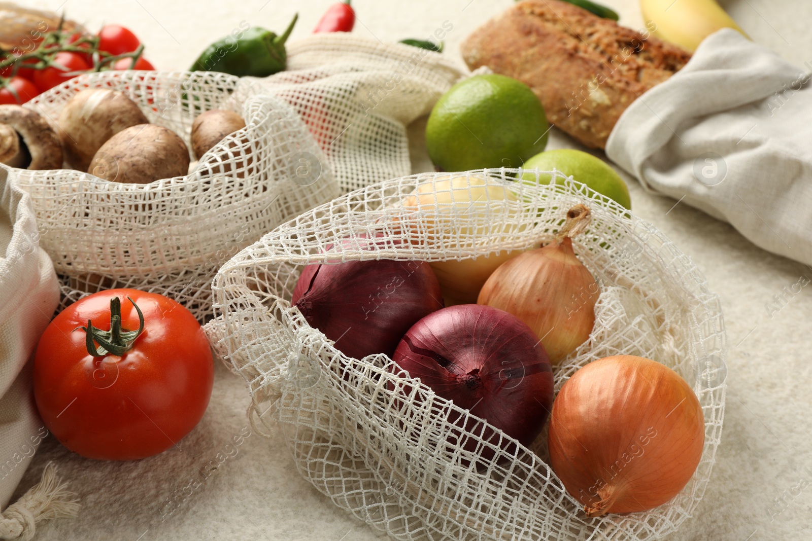 Photo of Eco bags with different food products on white textured table, closeup