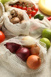 Photo of Eco bags with different food products on white textured table, closeup