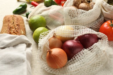 Photo of Eco bags with different food products on white textured table, closeup