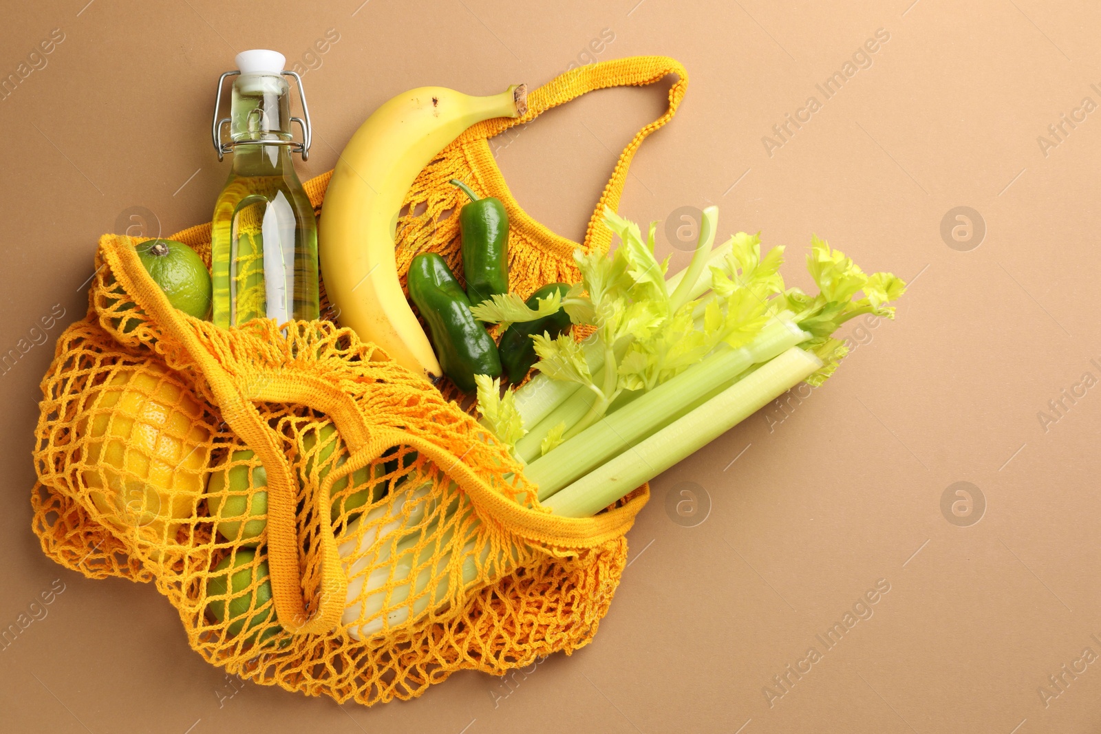 Photo of Eco bag with vegetables, fruits and bottle of drink on dark beige background, top view. Space for text