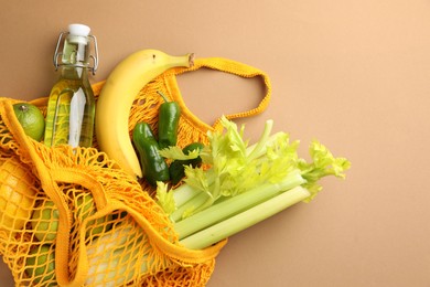 Photo of Eco bag with vegetables, fruits and bottle of drink on dark beige background, top view. Space for text