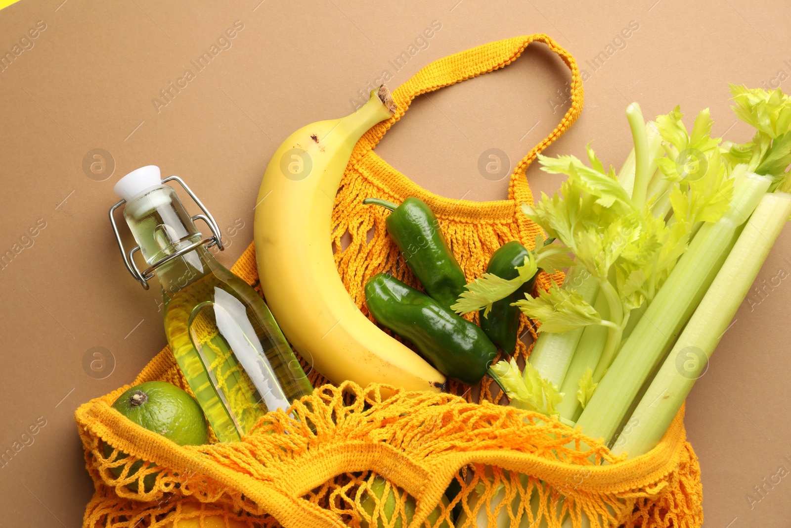 Photo of Eco bag with vegetables, fruits and bottle of drink on dark beige background, top view