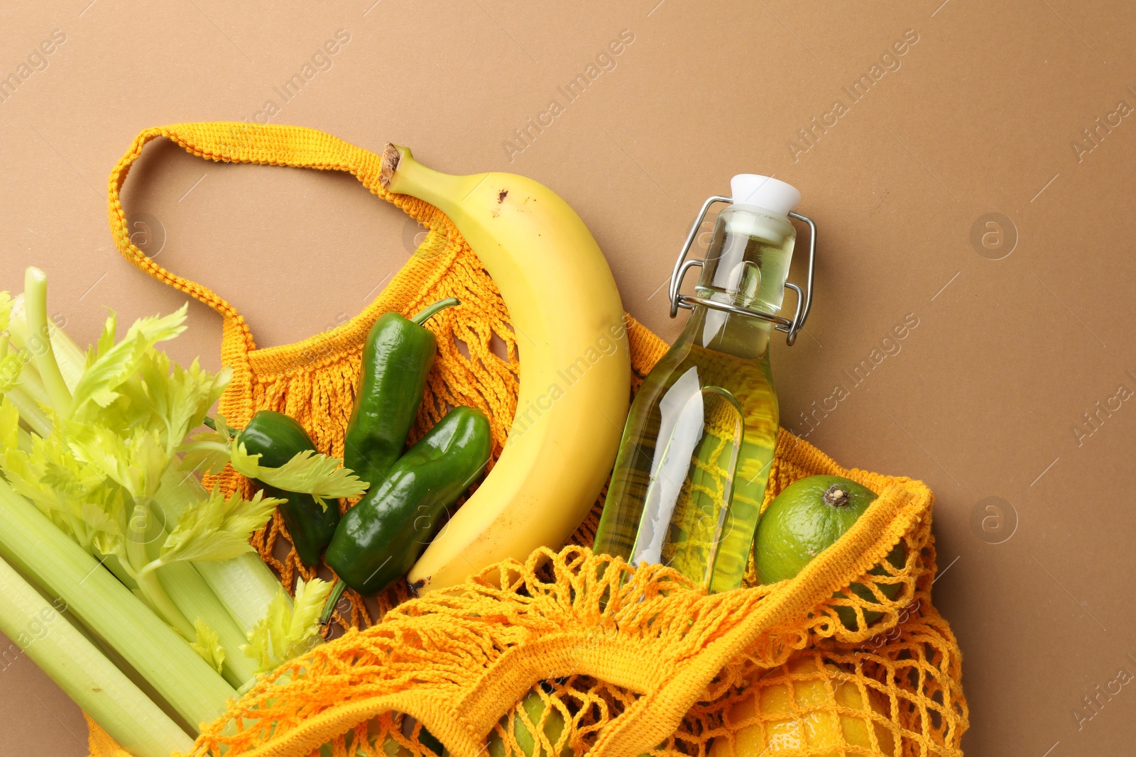 Photo of Eco bag with vegetables, fruits and bottle of drink on dark beige background, top view