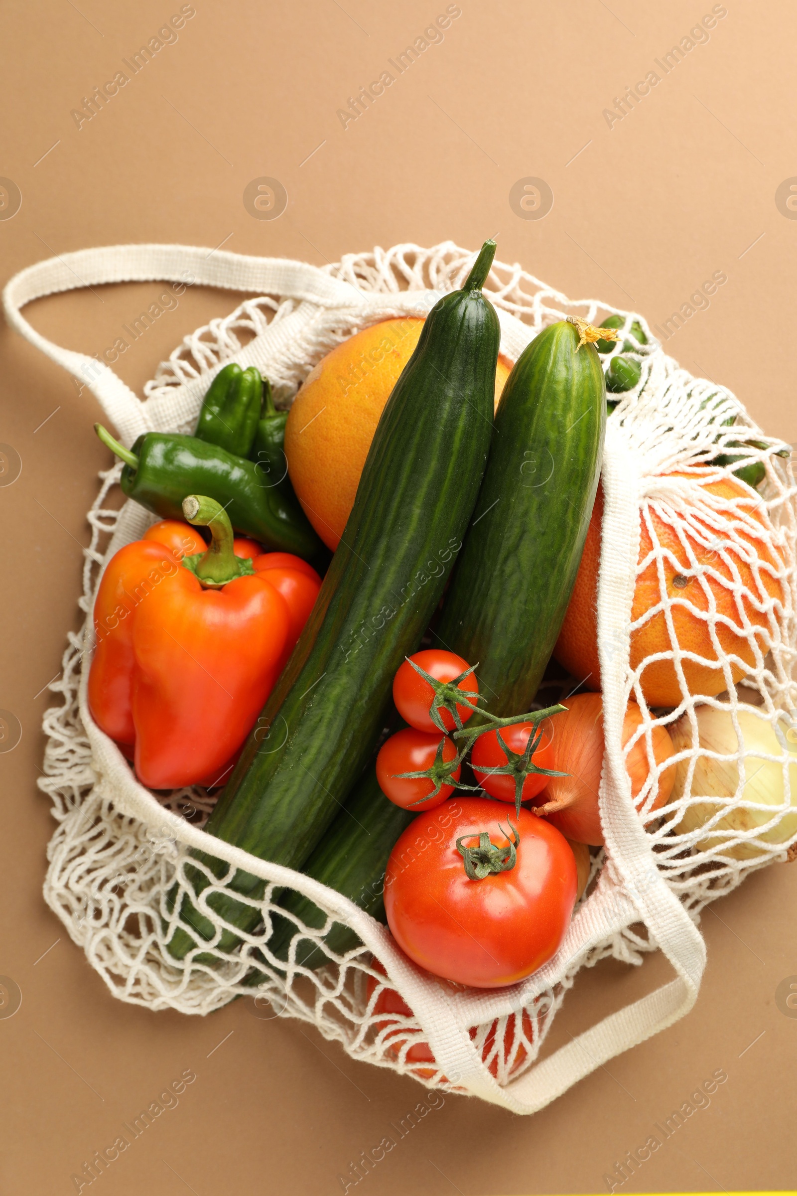 Photo of Eco bag with vegetables and fruits on dark beige background, top view