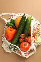 Photo of Eco bag with vegetables and fruits on dark beige background, top view