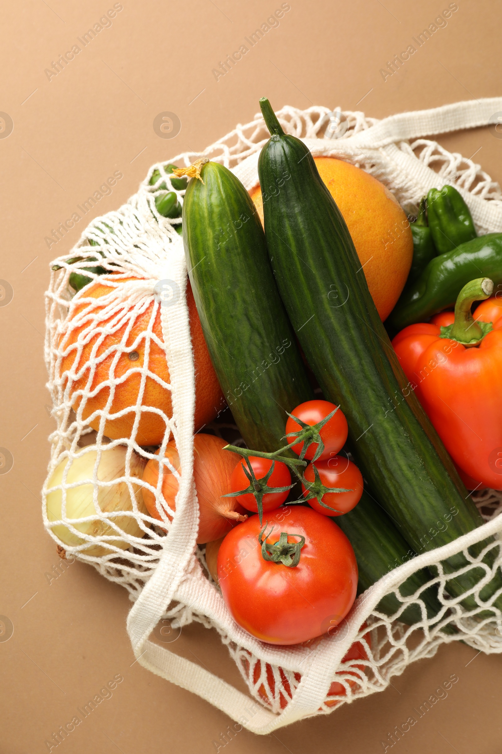 Photo of Eco bag with vegetables and fruits on dark beige background, top view