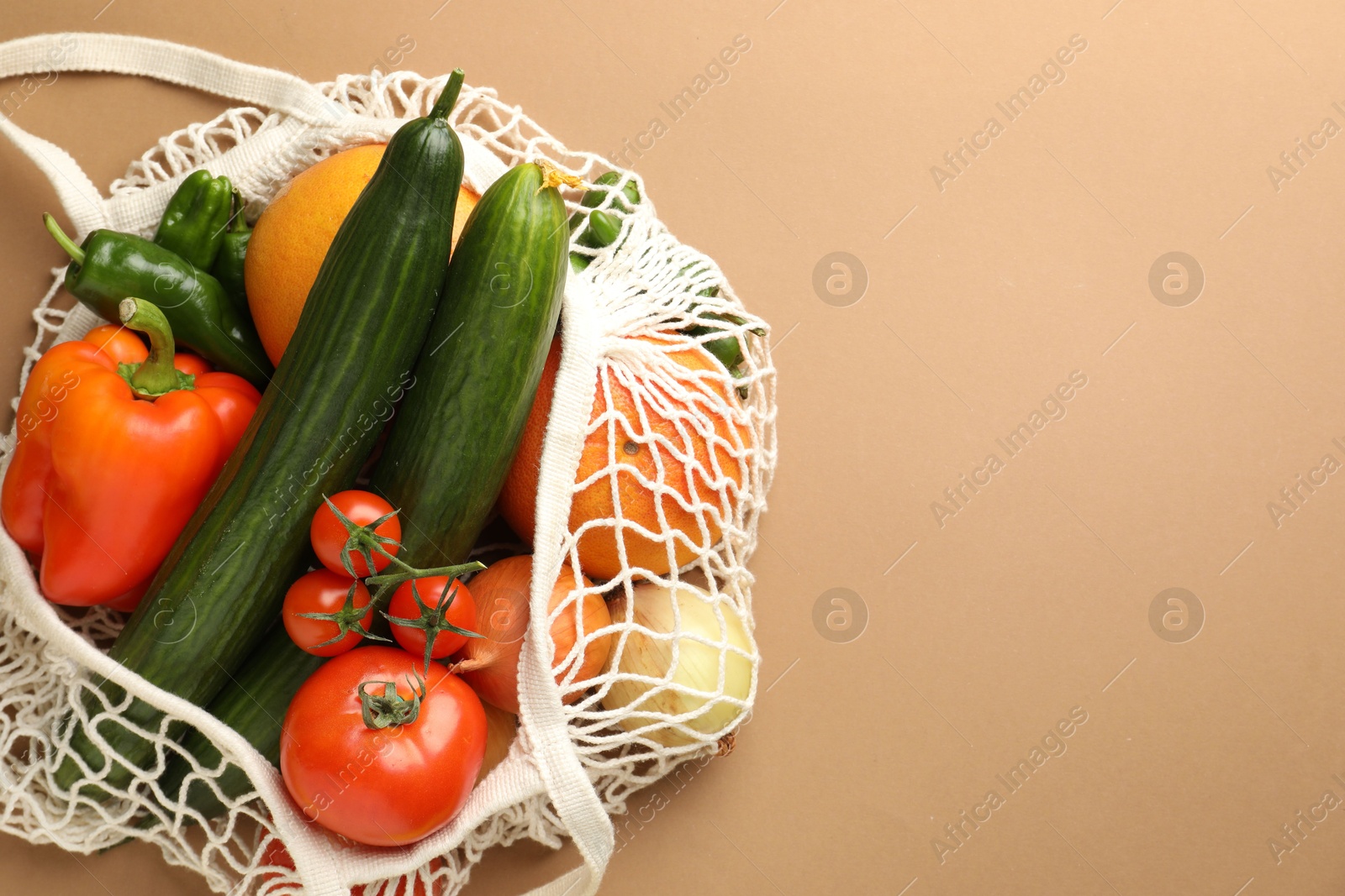 Photo of Eco bag with vegetables and fruits on dark beige background, top view. Space for text