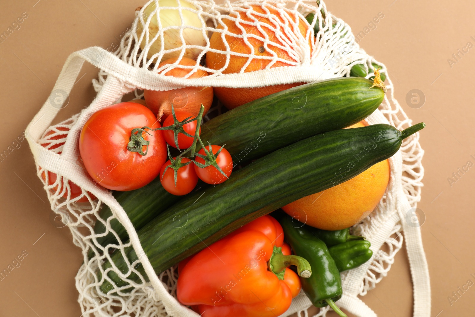 Photo of Eco bag with vegetables and fruits on dark beige background, top view