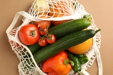 Photo of Eco bag with vegetables and fruits on dark beige background, top view