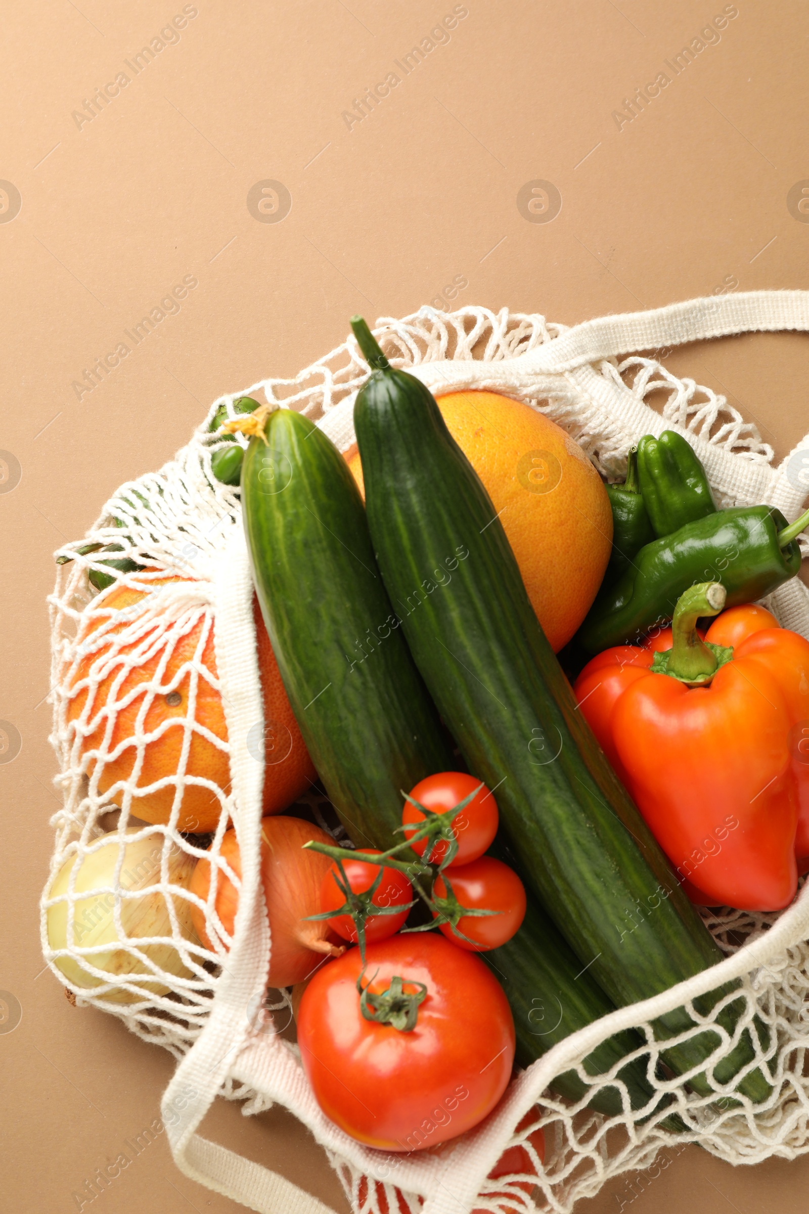 Photo of Eco bag with vegetables and fruits on dark beige background, top view