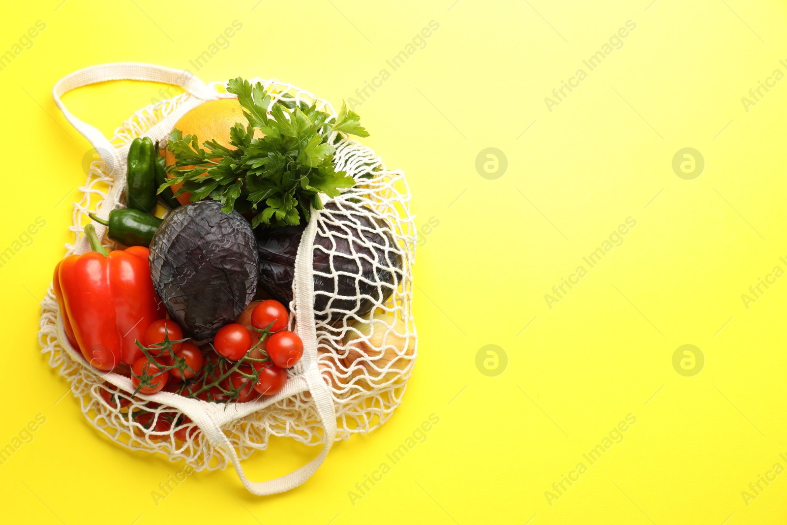 Photo of Eco bag with vegetables and grapefruit on yellow background, top view. Space for text