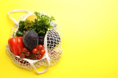 Photo of Eco bag with vegetables and grapefruit on yellow background, top view. Space for text