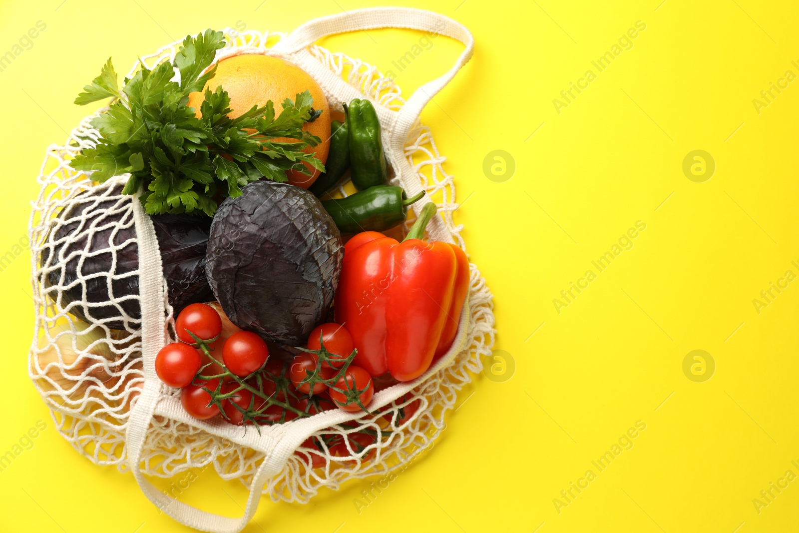 Photo of Eco bag with vegetables and grapefruit on yellow background, top view. Space for text