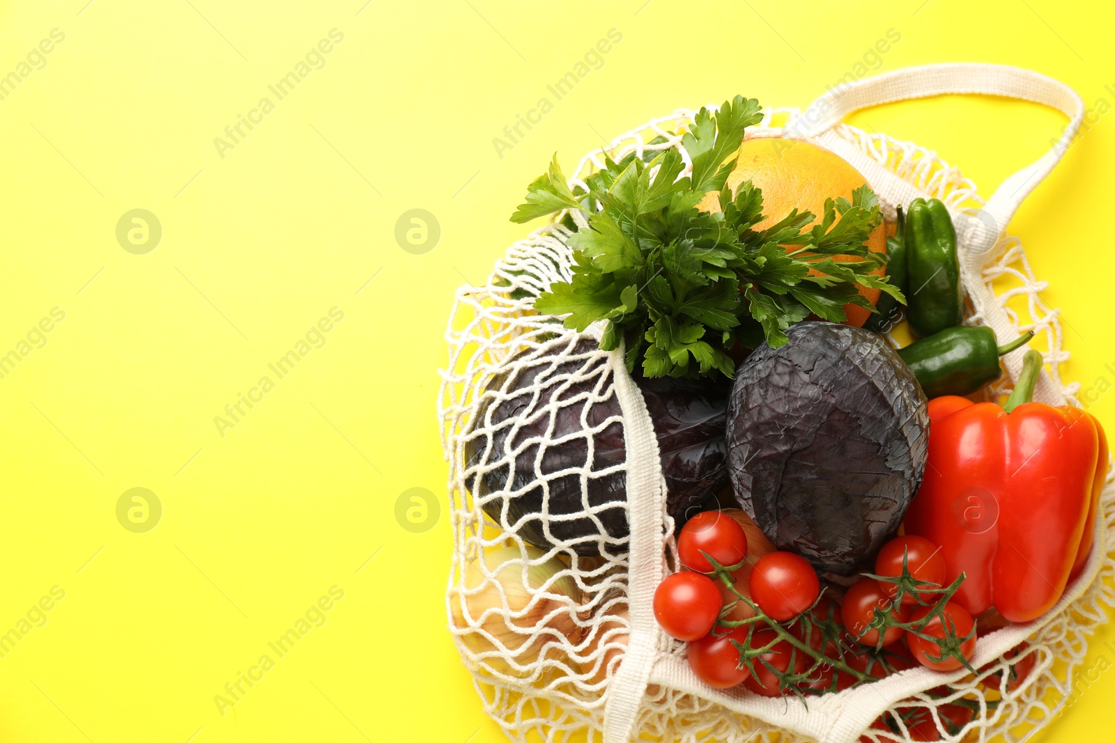 Photo of Eco bag with vegetables and grapefruit on yellow background, top view. Space for text