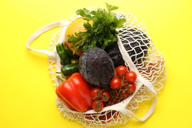 Photo of Eco bag with vegetables and grapefruit on yellow background, top view