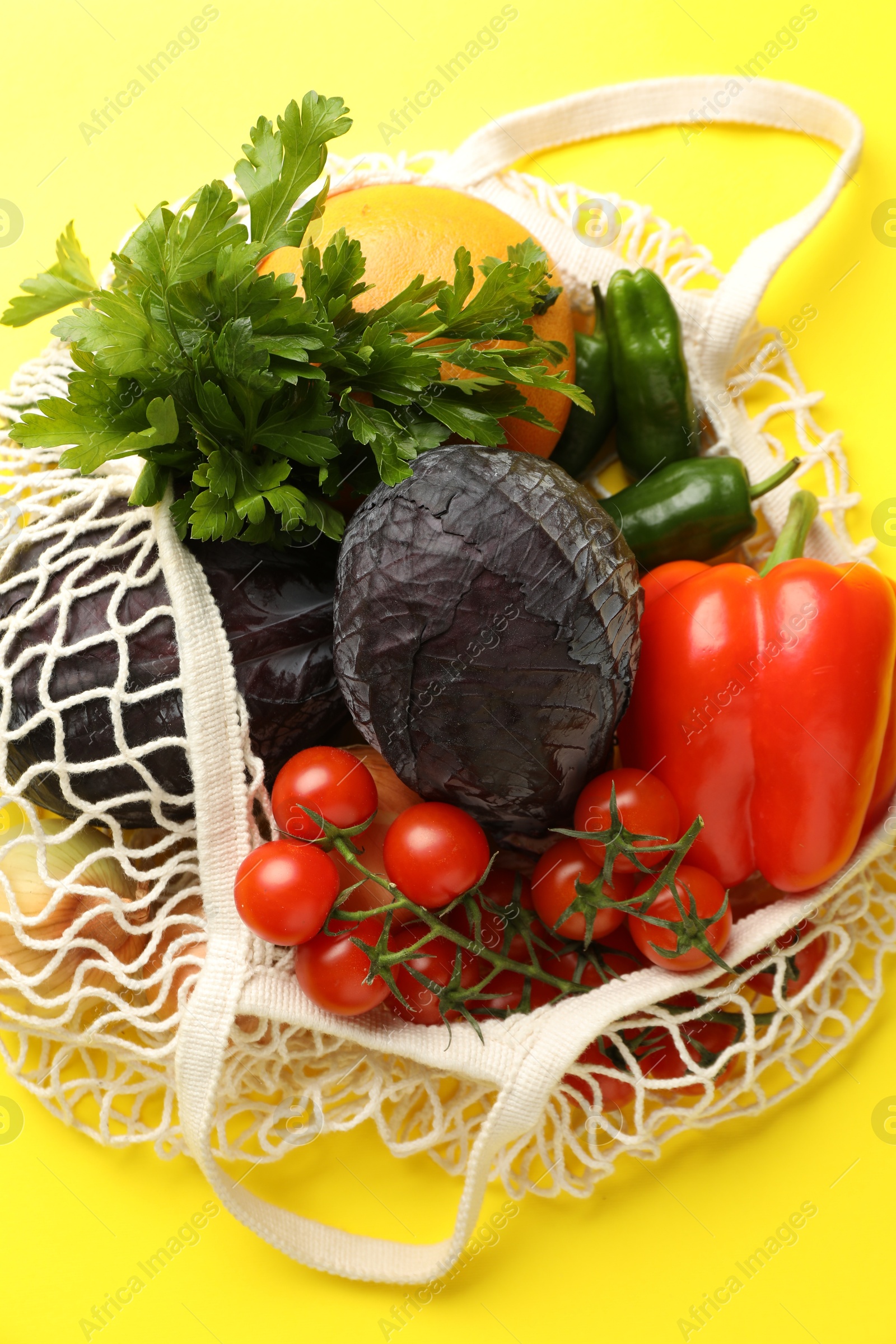 Photo of Eco bag with vegetables and grapefruit on yellow background, top view