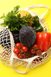 Photo of Eco bag with vegetables and grapefruit on yellow background, top view