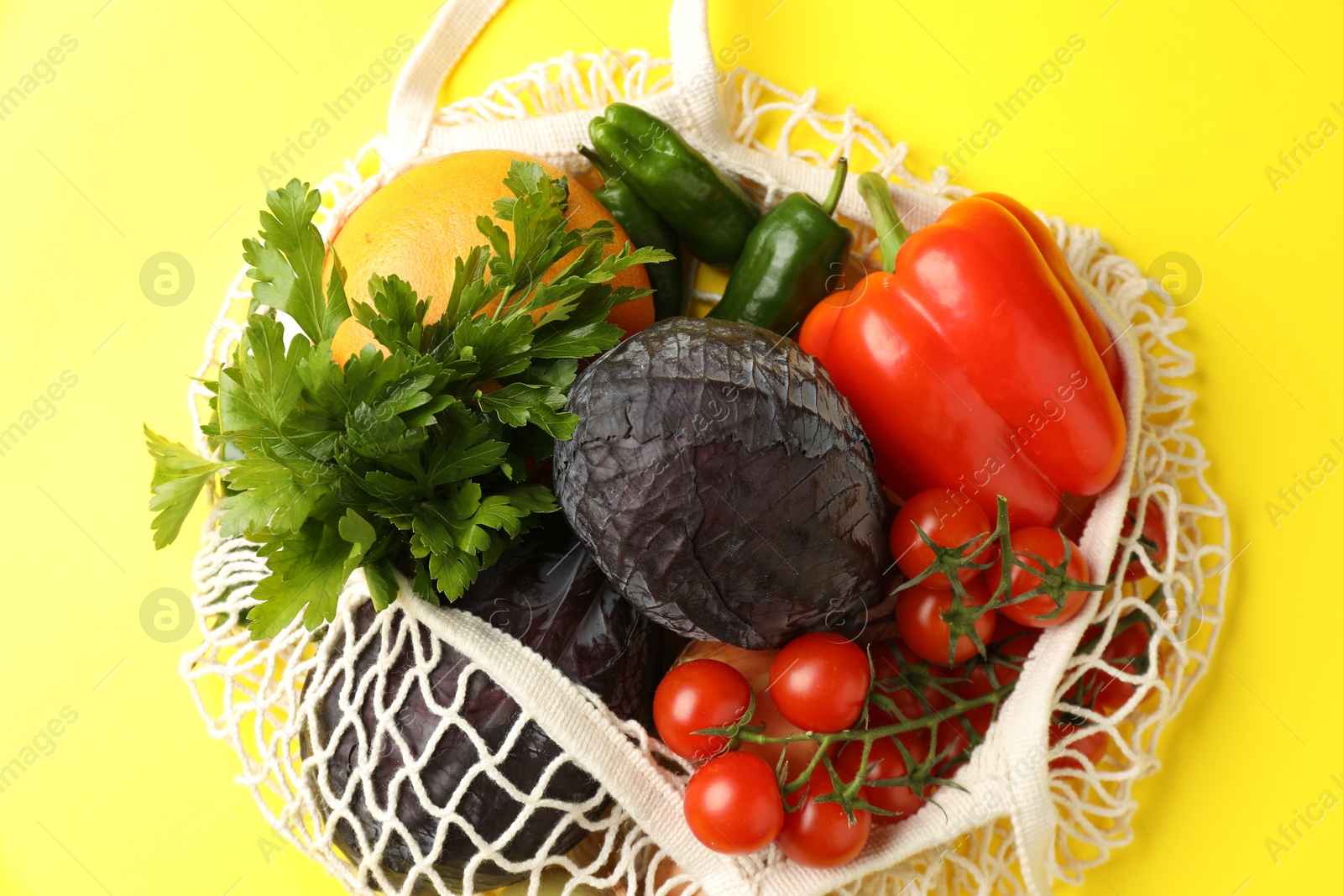 Photo of Eco bag with vegetables and grapefruit on yellow background, top view