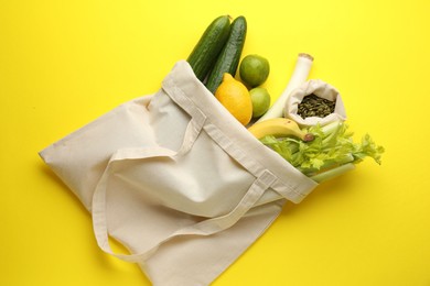 Photo of Eco bag with vegetables, fruits and pumpkin seeds on yellow background, top view