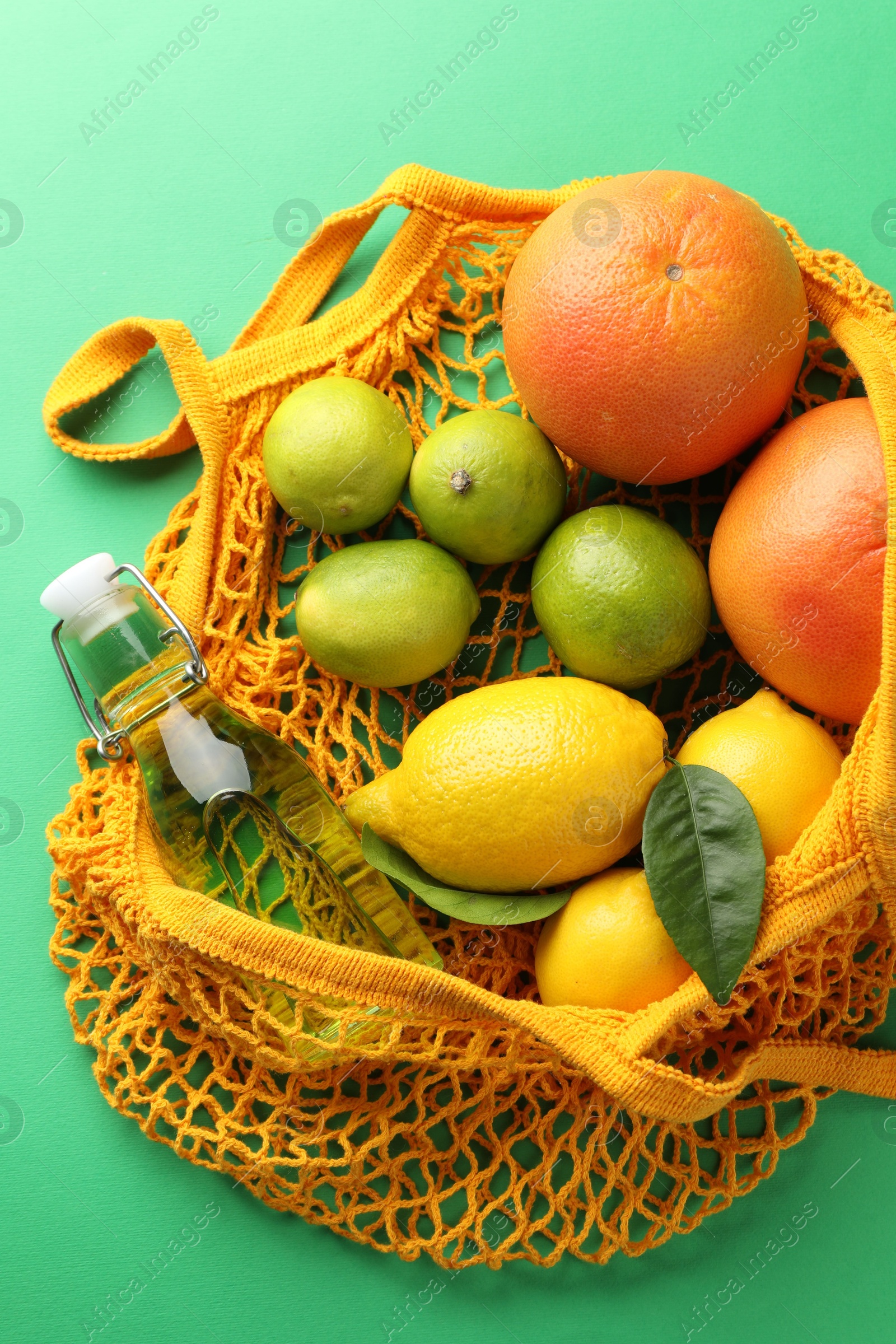 Photo of Eco bag with fruits and bottle of drink on green background, top view