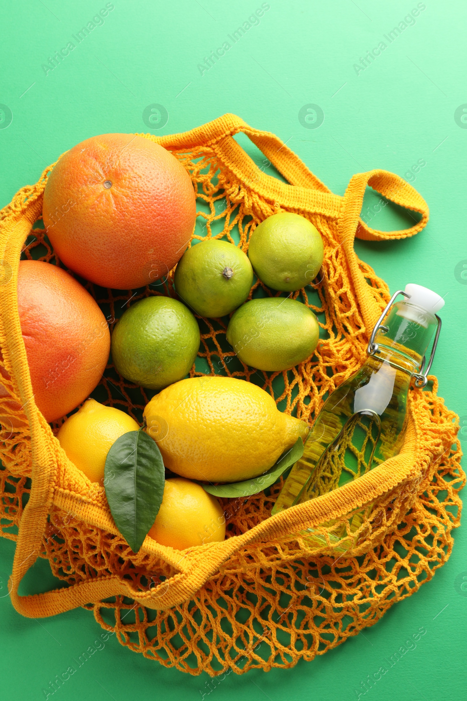 Photo of Eco bag with fruits and bottle of drink on green background, top view