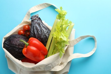 Photo of Eco bag with different vegetables on light blue background, top view