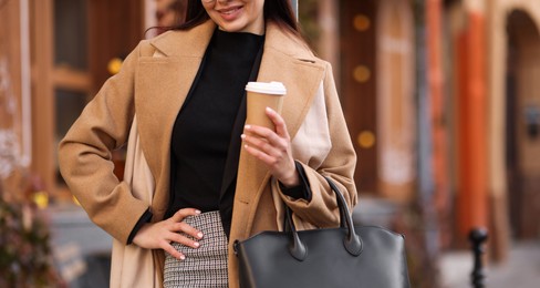 Photo of Smiling businesswoman in stylish outfit with paper cup outdoors, closeup. Space for text