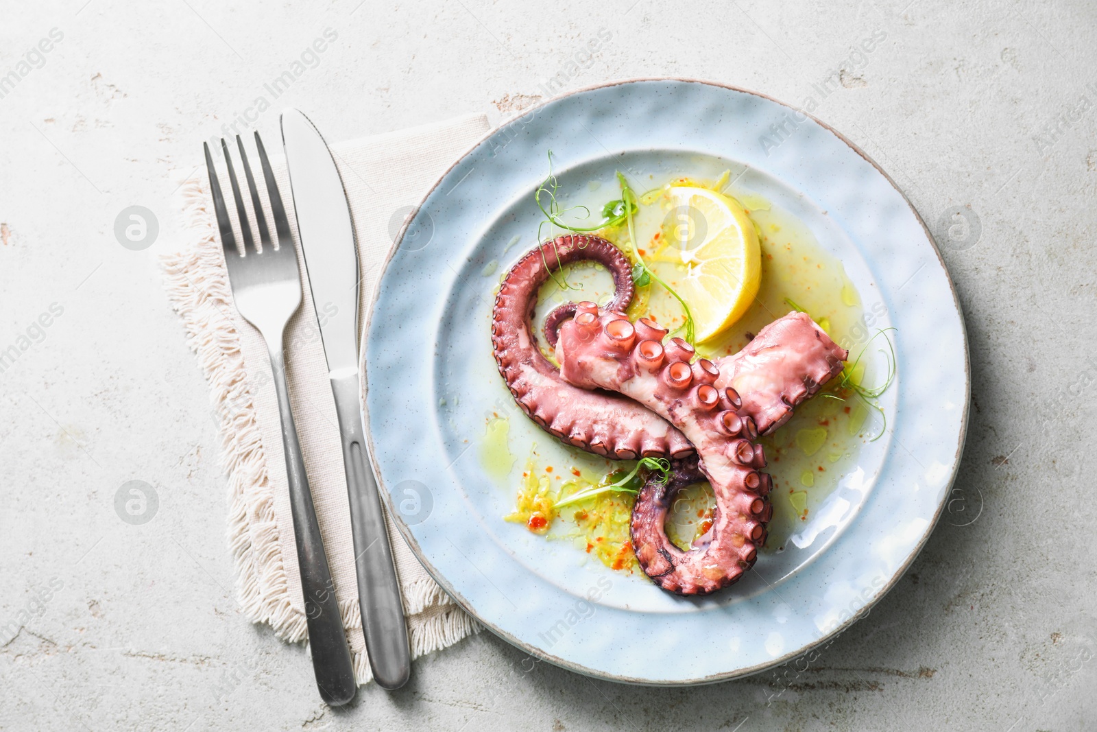 Photo of Appetizing octopus tentacles served on light table, top view