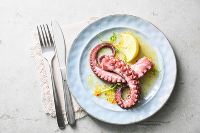 Photo of Appetizing octopus tentacles served on light table, top view