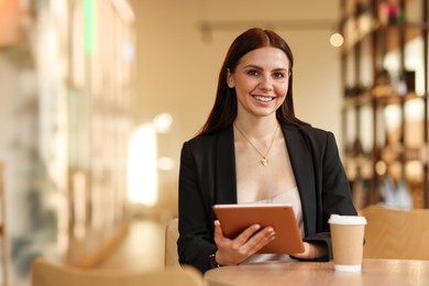 Photo of Woman in stylish formal suit with tablet and coffee at table indoors. Space for text