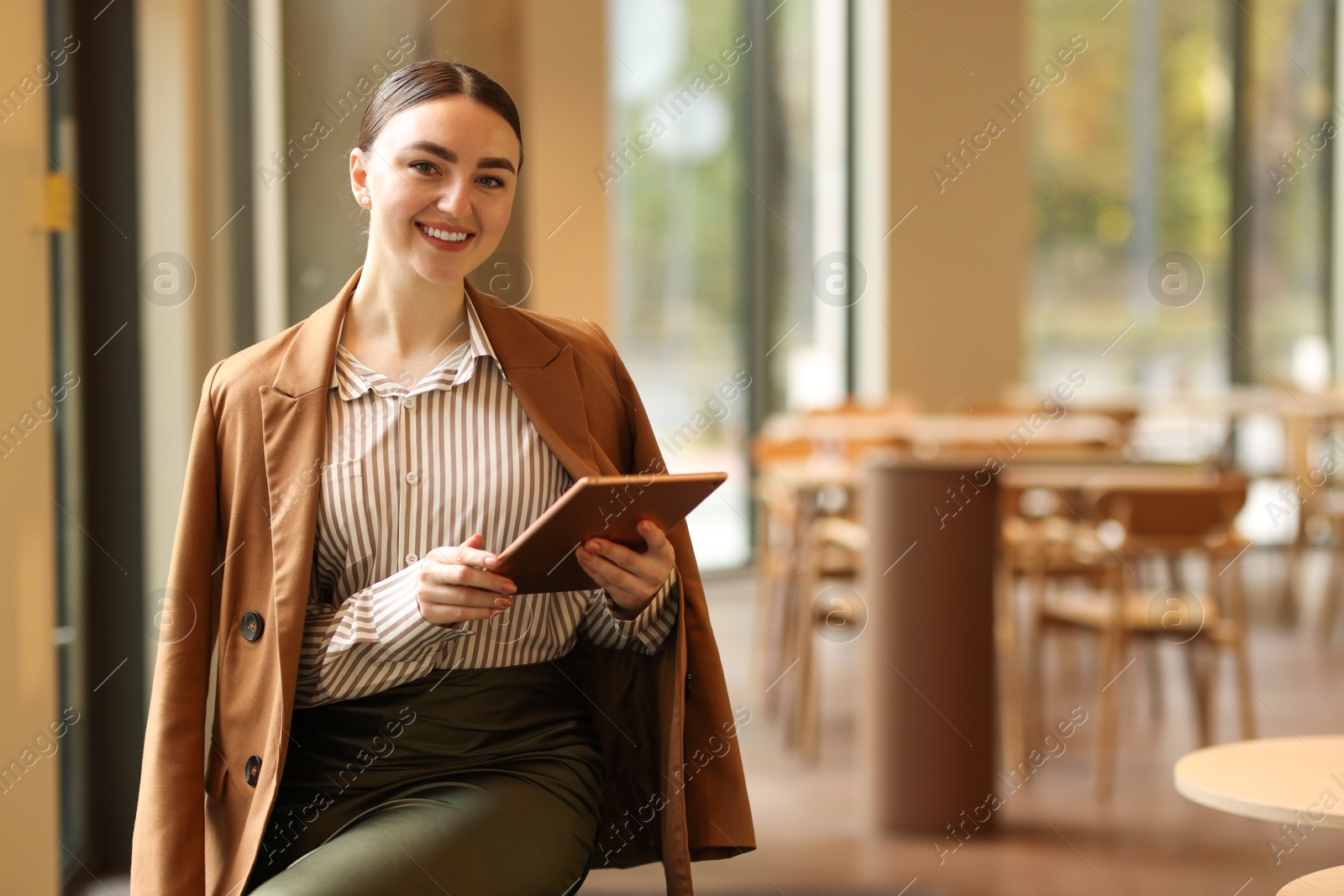 Photo of Woman in stylish formal suit with tablet indoors. Space for text