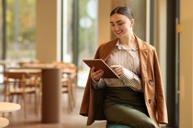 Photo of Woman in stylish formal suit with tablet indoors. Space for text