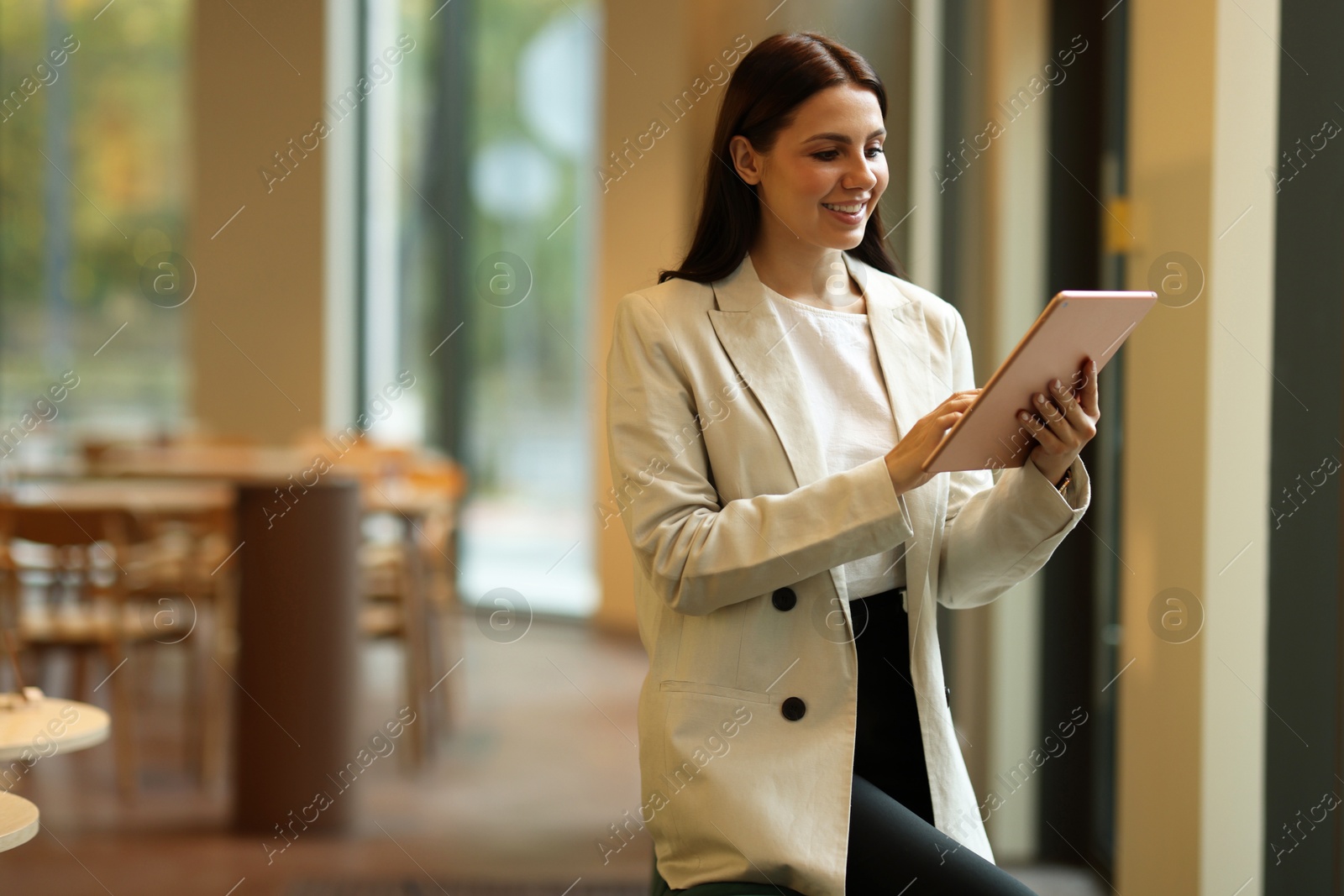 Photo of Woman in stylish formal suit with tablet indoors. Space for text