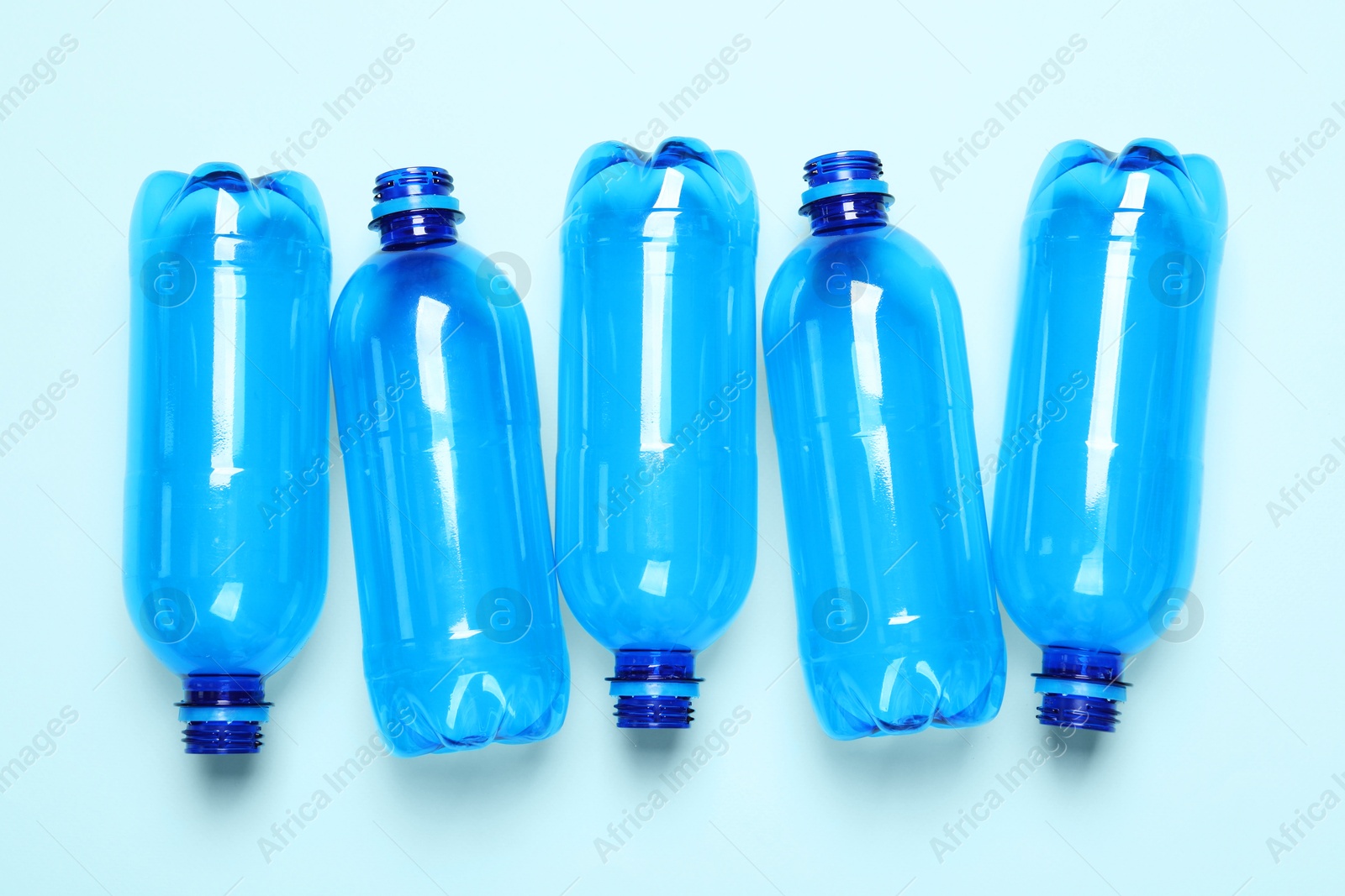 Photo of Empty plastic bottles on light blue background, flat lay