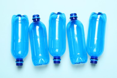 Photo of Empty plastic bottles on light blue background, flat lay